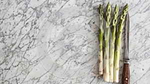 Green asparagus next to old knives on marble