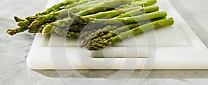 Green asparagus on a white cutting board close-up on the kitchen table