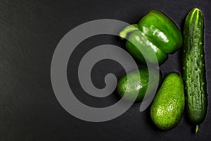 Green assortment vegetables, avocados, pepper and cucumber on a shale board, the concept of healthy eating, copy space, top view s