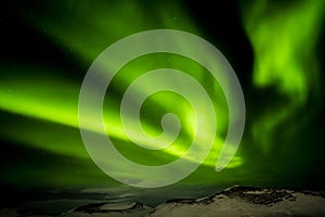 Green Aurora borealis streamers, northern Iceland with snow covered psuedo crater