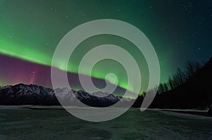 Green Aurora Over Mountains And A Frozen Lake