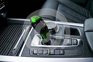 Green Automatic gear stick transmission of a modern car, multimedia and navigation control buttons. Car interior details.