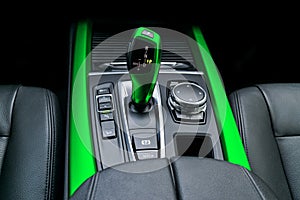 Green Automatic gear stick transmission of a modern car, multimedia and navigation control buttons. Car interior details. Transm