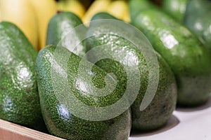 Green avocado on grocery shelf. Close-up of vitamin healthy fruits in supermarket. Fresh organic food, healthy eating