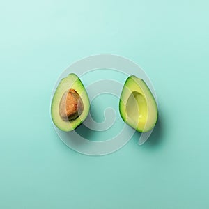 Green avocado halves with seed on blue pastel background. Creative minimal flat lay style with copy space. Summer food