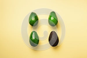 Green avocado and old black one on yellow background. Top view. Pop art design, creative summer food concept. Organic