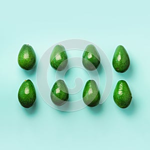 Green avocado pattern on blue background. Top view. Pop art design, creative summer food concept. Organic avocadoes in