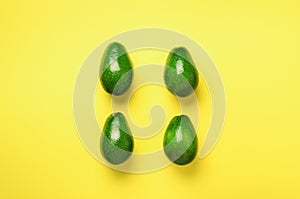 Green avocado pattern on yellow background. Top view. Pop art design, creative summer food concept. Organic avocadoes in