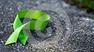 Green awareness ribbon on textured stone surface