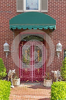 Green awning over a beautiful red door with decorative wrought iron gate