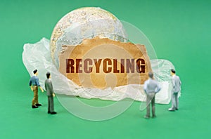 On a green background, blurry figures of people, a plastic bag, a globe and a sign with the inscription - recycling