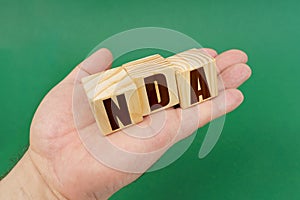 On a green background, in the hands of a person, cubes with the inscription - NDA