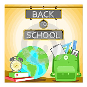 Green backpack and school supplies. Stack of books with alarm clock and globe. Back to school concept.