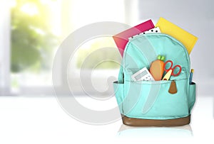 Green backpack with school supplies on white table,empty copy space backdrop