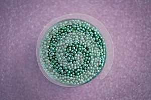Green ball crystal sugar sprinkle dots, on glitter pink background.