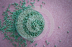 Green ball crystal sugar sprinkle dots, on glitter pink background.