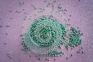 Green ball crystal sugar sprinkles dots, on glitter pink background.