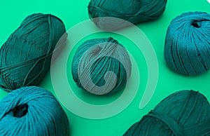 Green ball of yarn encircled with other balls of dark green yarn