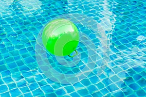 Green balls floating on blue water in the pool.