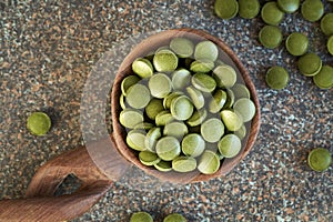 Green barley grass tablet on a wooden spoon, top view
