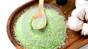 Green bath salt with wooden spoon on tray