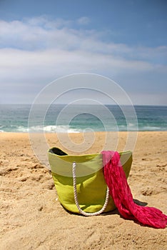 Green beach bag on the seacoast and pink shawl