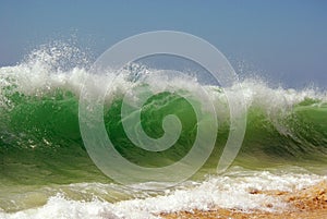 A green beachbreak wave over sky