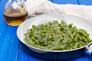 Green beans on frying pan on wooden background