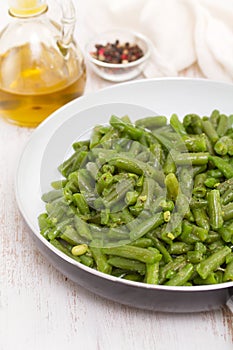 Green beans on frying pan on wooden background