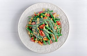 Green beans salad with bruschettas, Red, Yellow Tomatoes and flaked almond on white plate