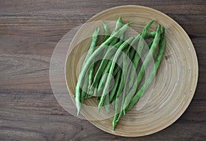 Green beans on a wooden plate