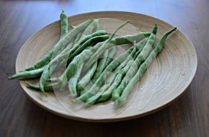 Green beans on a wooden plate