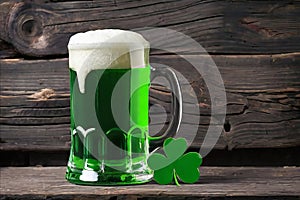 Green beer with clover leaves on wooden table on background of a pub. St. Patrick's day.