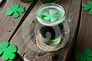 Green beer with clover leaves on wooden table on background of a pub. St. Patrick's day.