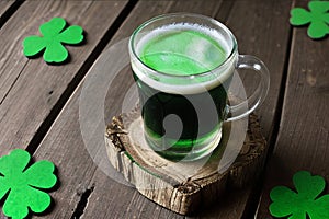 Green beer with clover leaves on wooden table on background of a pub. St. Patrick's day.