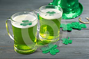 Green beer and clover leaves on wooden table. St. Patrick`s Day celebration