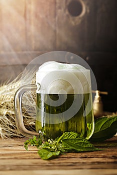 Green beer on a wooden table, in the back of the original oak barrel and wheat cob. This beer is traditionally served on St. Patri