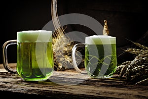 Green beers on a wooden table, in the back of the original oak barrel and wheat cob. This beer is traditionally served on St. Patr