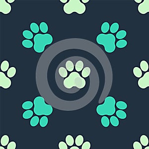 Green and beige Paw print icon isolated seamless pattern on blue background. Dog or cat paw print. Animal track. Vector