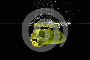 Green bellpepper falling into water with a splash
