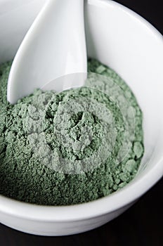 Green bentonite clay powder in a bowl. Clay texture close-up. Diy mask and body wrap recipe. Natural beauty treatment and spa