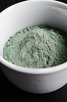Green bentonite clay powder in the  white bowl. Diy facial mask and body wrap recipe. Natural beauty treatment and spa. Copy space