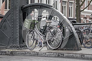 Green bicycle with basket parked on a bridge in Amsterdam