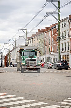 Green big rig tip truck running on the city street