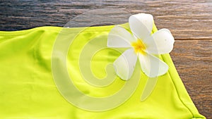 Green bikini with white flower, plumeria flower on wood, summer