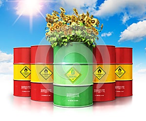 Green biofuel drum with sunflowers in front of red oil or gas ba