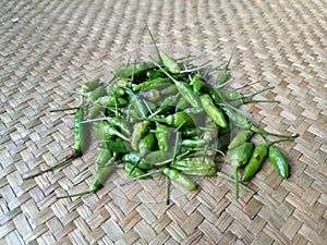 Green bird& x27;s eye chilies on a woven pandan leaf mat