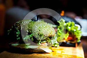 Green, black mini burgers with vegetables .