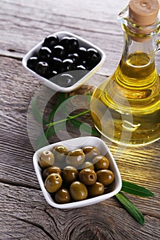 Green and black olives in bowl on a grey wooden background