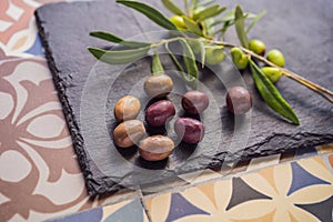 Green and black olives with leaves on dark background. Copy space, flat lay